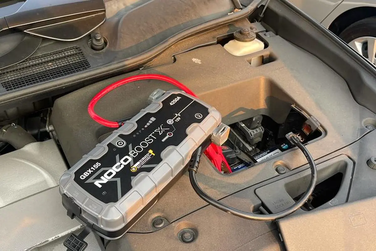NOCO Boost jump pack clamped to a car battery during a Guerra Towing jump start in San Jose