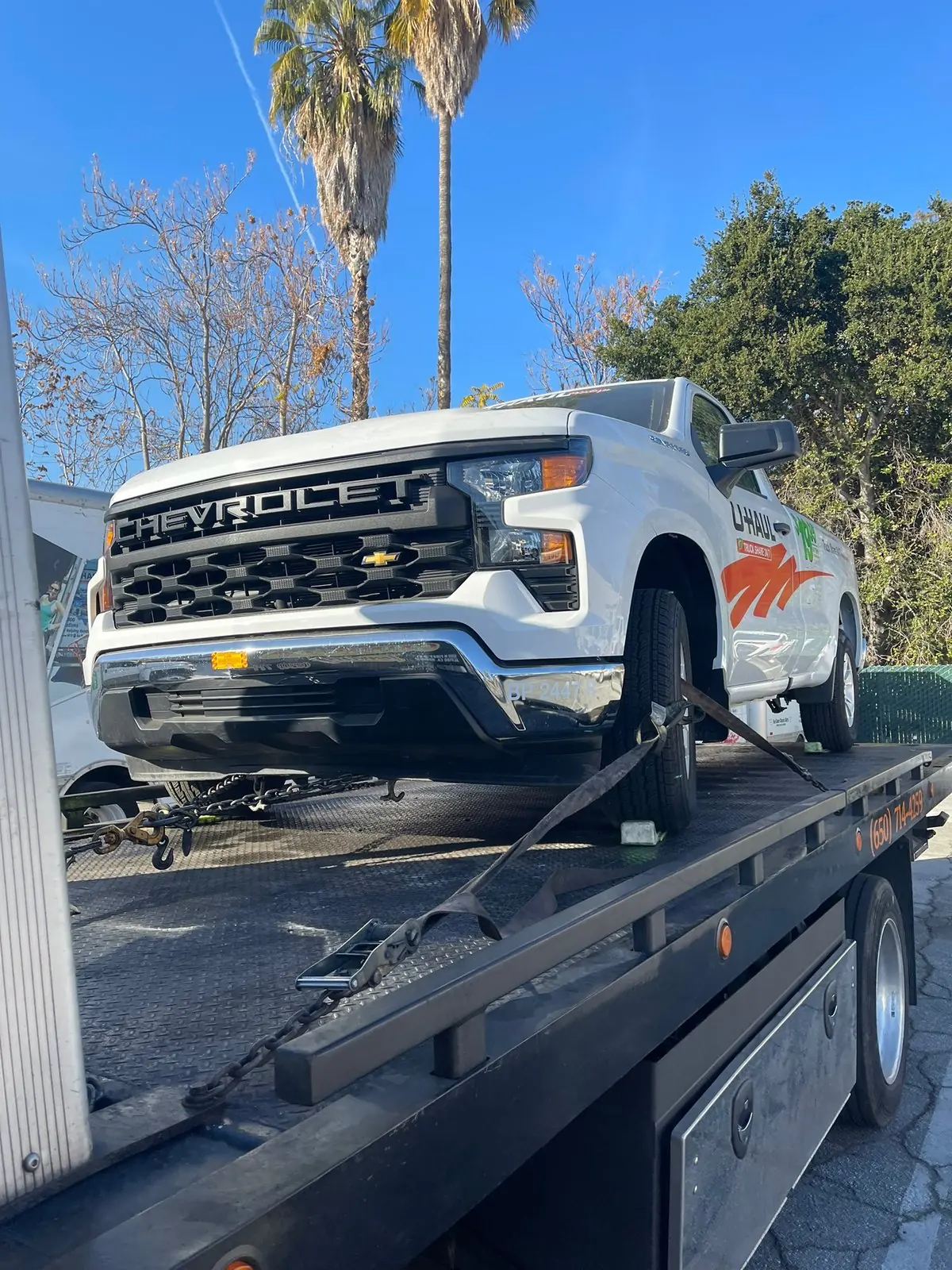 Pickup strapped down on the deck of a Guerra Towing flat bed truck