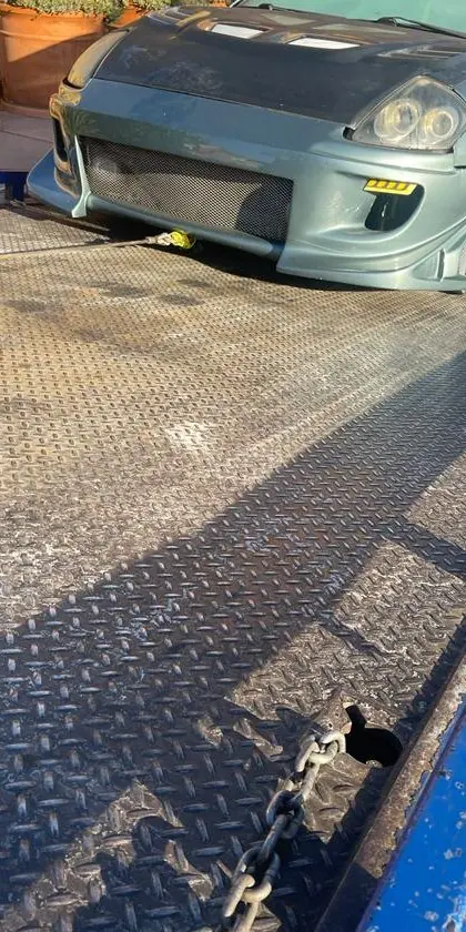 Un auto personalizado con suspensión rebajada está siendo cargado en la plataforma de un grúa de plataforma de Guerra Towing