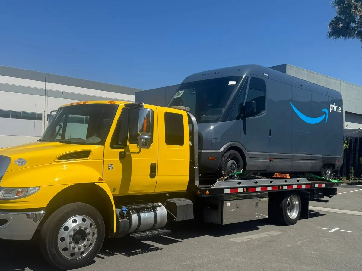 Grúa de plataforma de Guerra Towing que transporta una camioneta de reparto en San José
