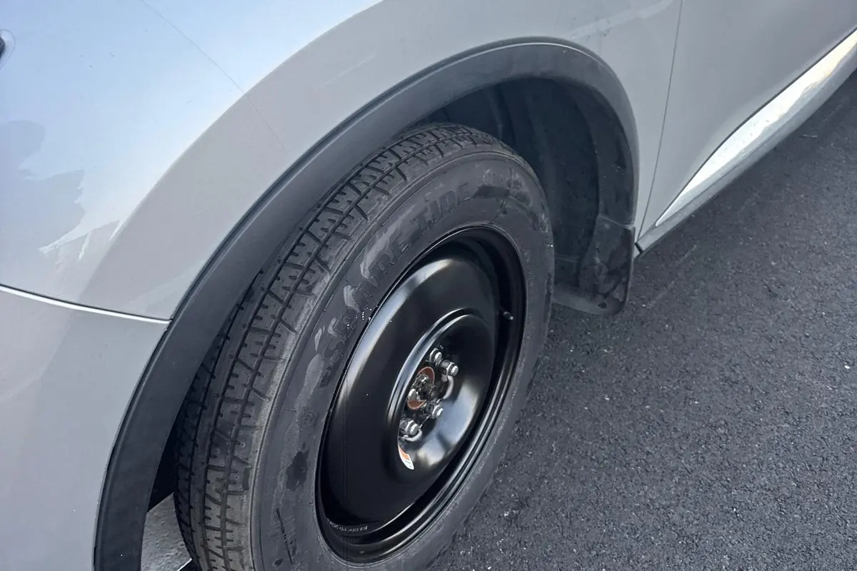 Compact spare tire put on a silver SUV at the roadside in San Jose