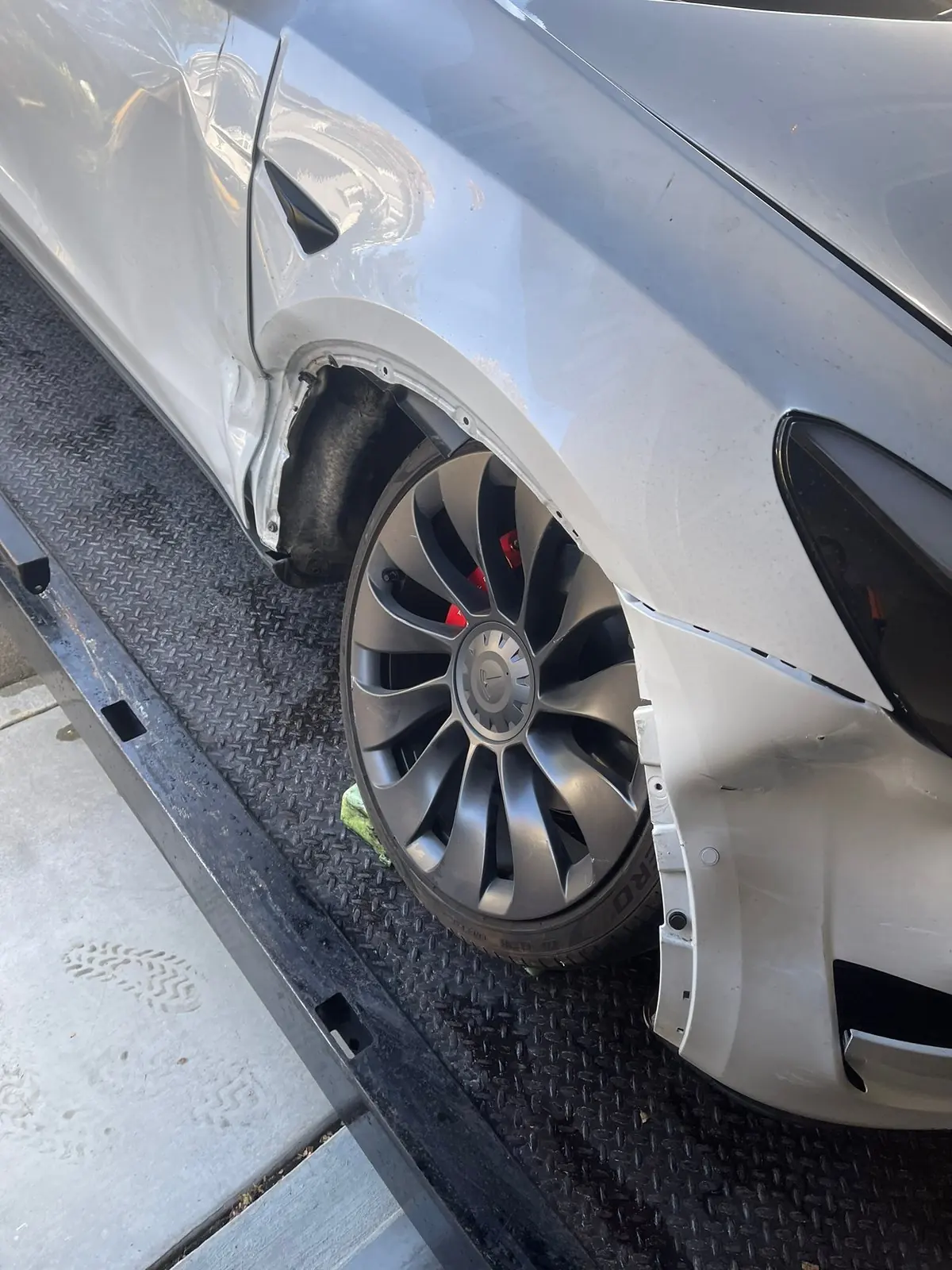 Rueda dañada en un accidente, sujeta con un calzo en la plataforma de un camión de Guerra Towing