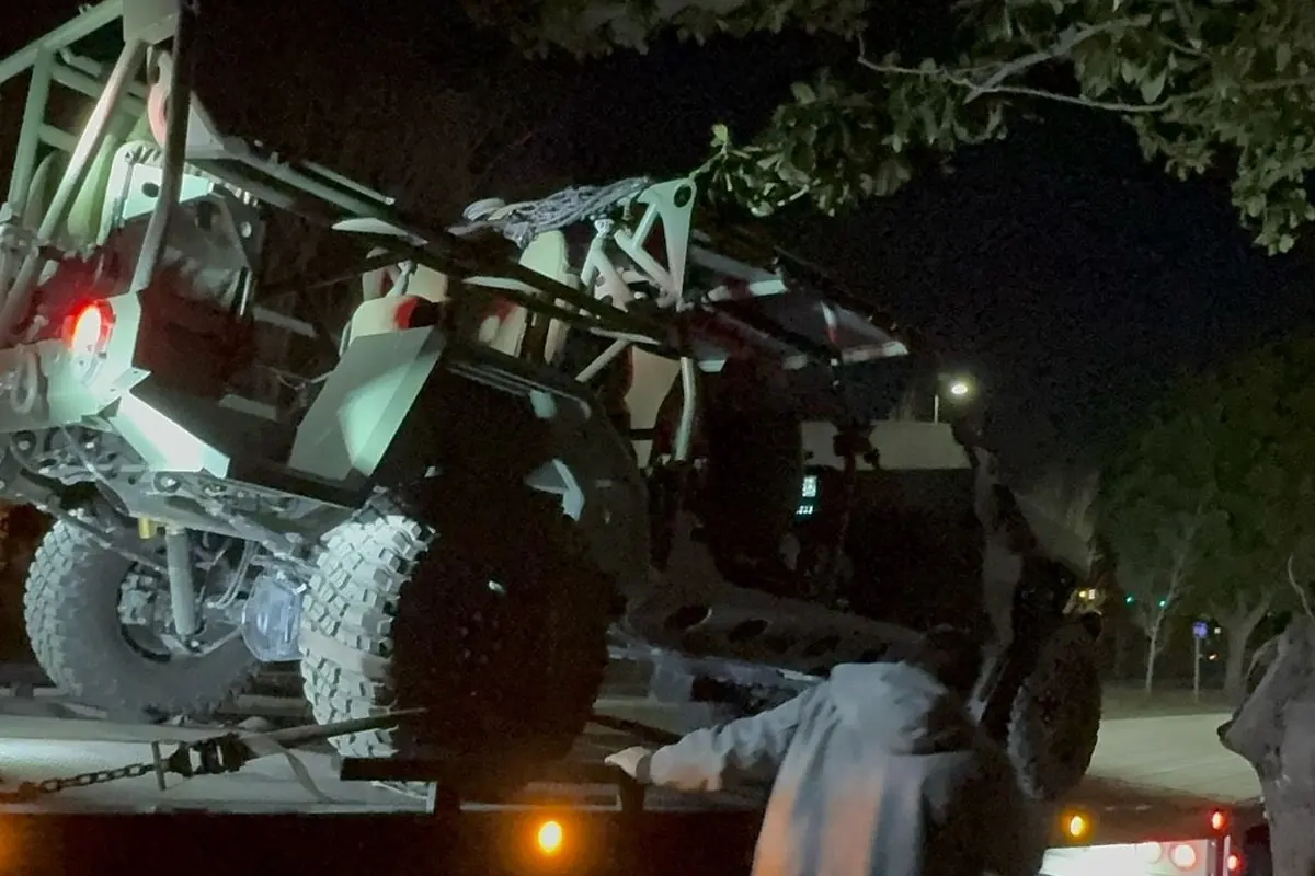 Off-road buggy drawn onto a Guerra Towing truck at night with the crew securing it
